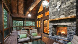 A log cabin with a stone fireplace, wooden deck, and outdoor seating. - The Leaflet | Hocking Hills, Swim Spa, Theater (Laurelville)