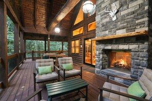 A log cabin with a stone fireplace, wooden deck, and outdoor seating. - The Leaflet | Hocking Hills, Swim Spa, Theater (Laurelville)