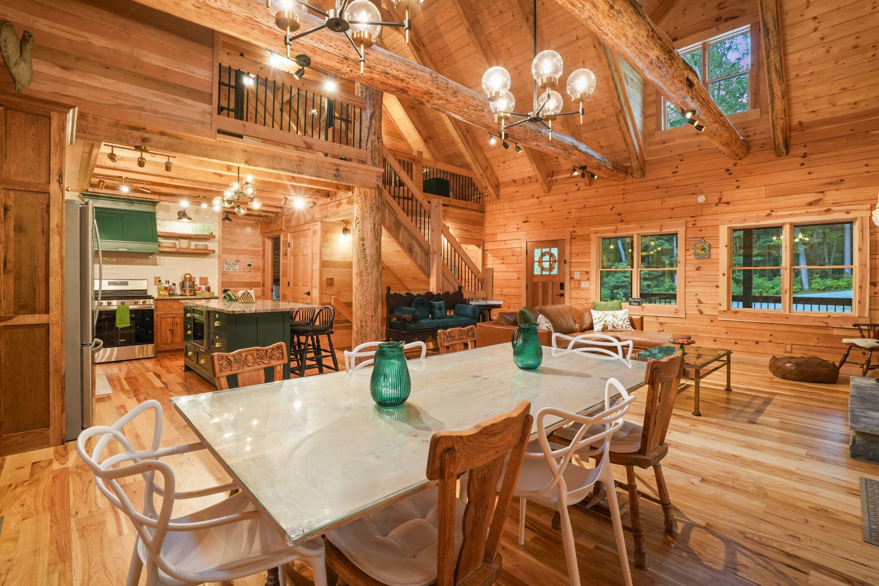 Een houten chalet interieur met een eethoek, keuken en een trap naar een verdieping.