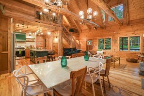 A rustic cabin interior with a dining area, kitchen, and a loft bedroom.