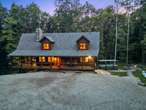 A log cabin with a porch, a hot tub, and a deck.
