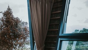 A room with a large window, wooden floor, and a curtain. - Skylake Villa (Kintamani)