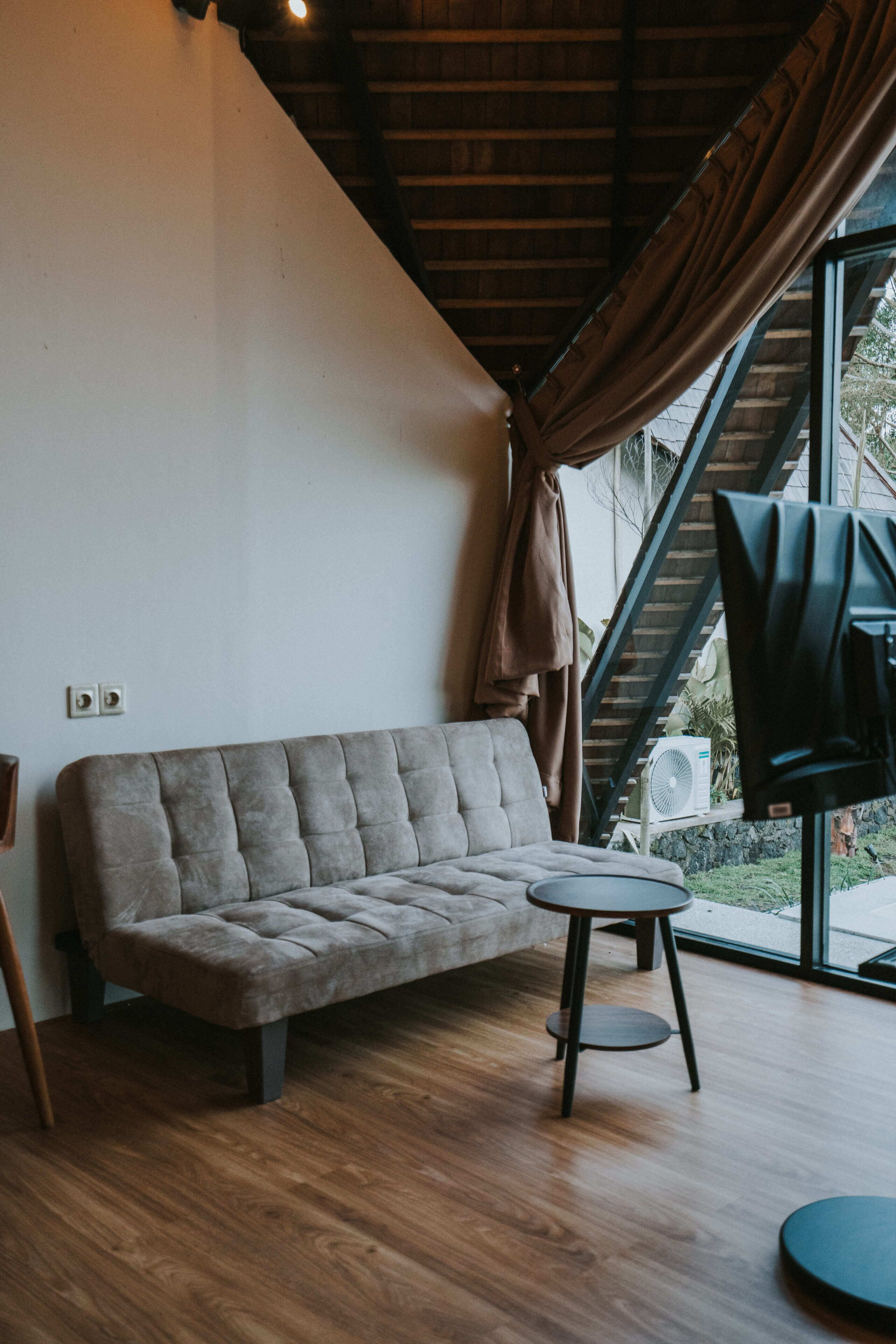 Una habitación moderna con sofá, una mesita redonda y un ventilador.