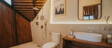 Een badkamer met toilet, douche, wastafel, spiegel en een fotokader aan de muur.