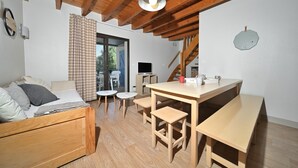 Una habitación acogedora con una cama de madera, una mesita con bancos, un televisor y una escalera.