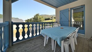 Un espacio al aire libre techado con una mesa y sillas, vistas al campo y una puerta con contraventana azul.
