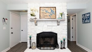 A fireplace with a stone facade, a framed map of Lake Ozarks, and a sign that says "GO JUMP IN THE LAKE".