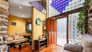 Un salon comprenant un canapé, une table basse, un meuble en bois et une grande fenêtre avec des vitres bleues.
