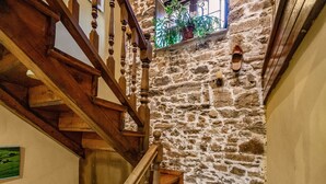 Un escalier en pierre avec des rampes en bois et une petite fenêtre ornée de plantes.