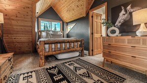 A bedroom with a wooden bed, a dresser, a rug, and a horse painting on the wall.