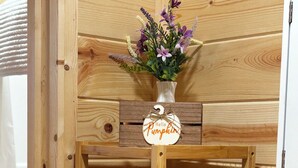 A wooden shelf with a vase of flowers, a jar with 'Give Thanks' written on it, and a potted plant.