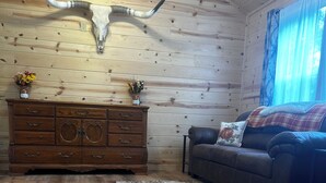 A wooden cabin interior with a large wooden dresser, a sofa, and a decorative antler on the wall.