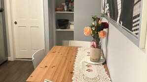 En matplats med ett träbord, vita stolar, en spetsduk och en vas med blommor.