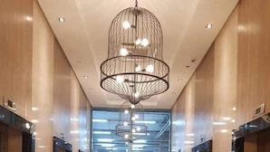 A modern elevator lobby with a polished floor, a central chandelier, and a view of the building's interior through large windows. - One Uptown Residence (Taguig)