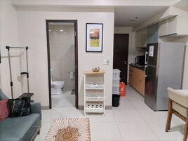 Un espacio habitable pequeño con kitchenette, baño y sofá.