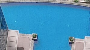 A rectangular pool with a clear blue water surface, surrounded by a tiled walkway. - One Uptown Residence (Taguig)