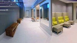 A modern hotel lobby with a reception desk, seating area with sofas, and a large mirror wall. - One Uptown Residence (Taguig)