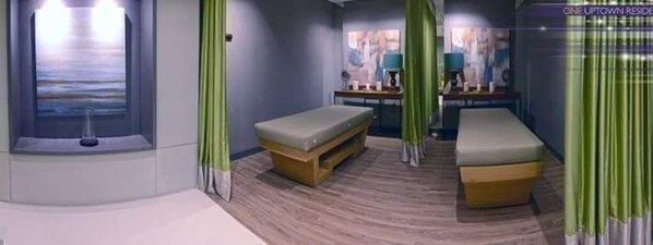 A room with two beds, a small table, and a wall-mounted TV.