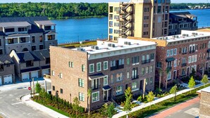 A multi-story building with a brick facade, large windows, and a flat roof. - Luxe New Construction with River View, Pool Table (Savannah)