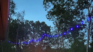 An outdoor deck with a fire feature, seating, and string lights. - Gorgeous New Cabin with 70Acres!Trails, Waterfalls and Amazing Rock Formations! (Cub Run)