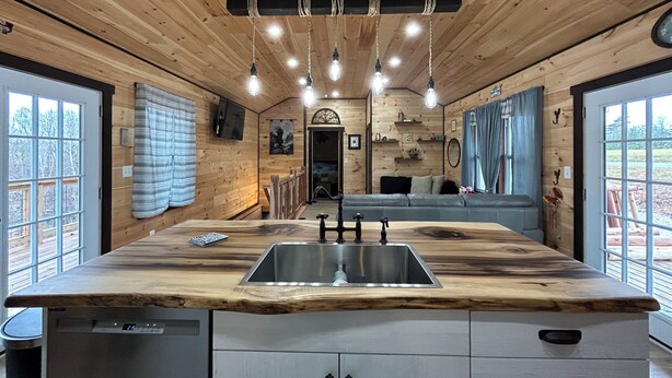 A modern kitchen with a wooden countertop, stainless steel sink, and hanging pendant lights. - Gorgeous New Cabin with 70Acres!Trails, Waterfalls and Amazing Rock Formations! (Cub Run)