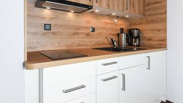 Eine moderne Küche mit Holzschränken, Edelstahlgeräten und einer schwarzen Arbeitsplatte.