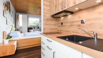 Eine moderne Küche mit Holzschränken, einem schwarzen Spülbecken und Edelstahlgriffen.