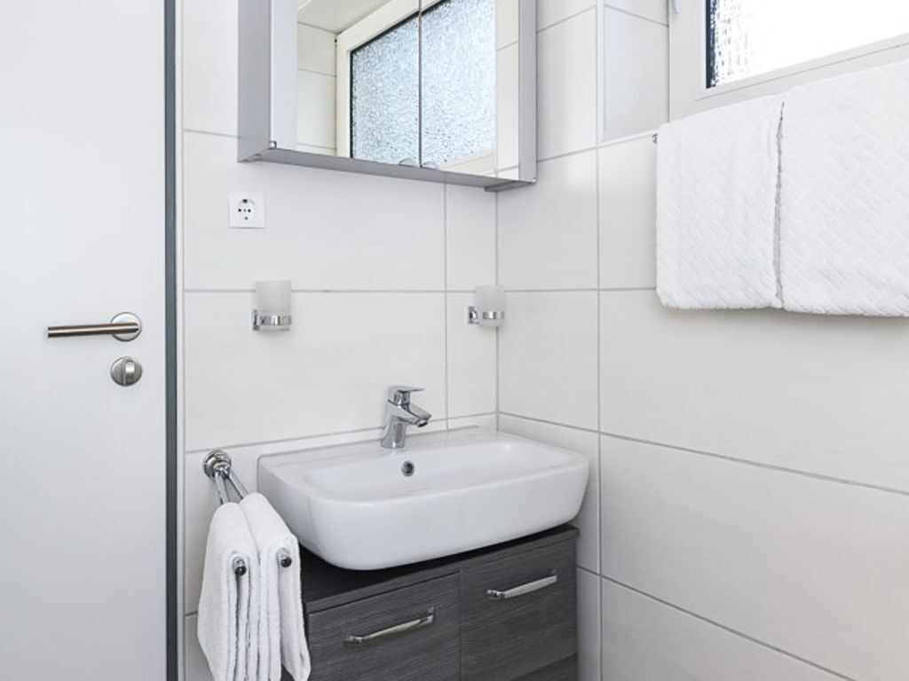 Ein modernes Badezimmer mit Waschbecken, Spiegel und Handtuchhalter.