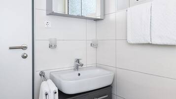 Ein modernes Badezimmer mit Waschbecken, Spiegel und Handtuchhalter.