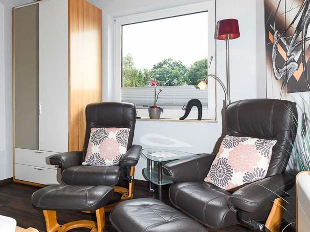 Ein modernes Wohnzimmer mit Ledersofas, einem Glastisch und Blick ins Grüne.