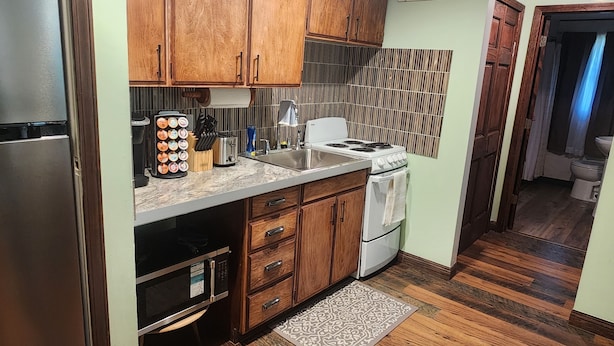 A kitchen with wooden cabinets, a stainless steel refrigerator, a stove, and a sink. - Relaxing, Peaceful 1-bedroom Pet- Friendly Apartment  (Mason City)