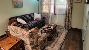 A cozy living room with a plaid sofa, floral armchair, and a small wooden table with a book. - Relaxing, Peaceful 1-bedroom Pet- Friendly Apartment  (Mason City)
