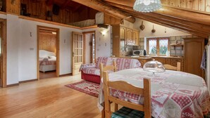 A cozy, wooden interior with a dining area, a kitchen, and a bedroom. - Apartment 'Piccolo Paradiso' with Mountain View, Private Garden and Wi-Fi (Gimillan)