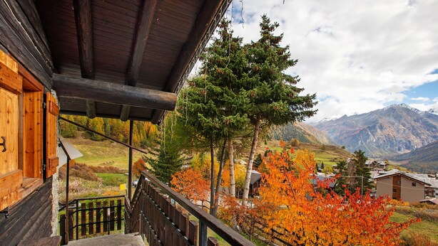 A wooden cabin with a balcony, a staircase, and a view of autumn trees and mountains. - Apartment 'Piccolo Paradiso' with Mountain View, Private Garden and Wi-Fi (Gimillan)