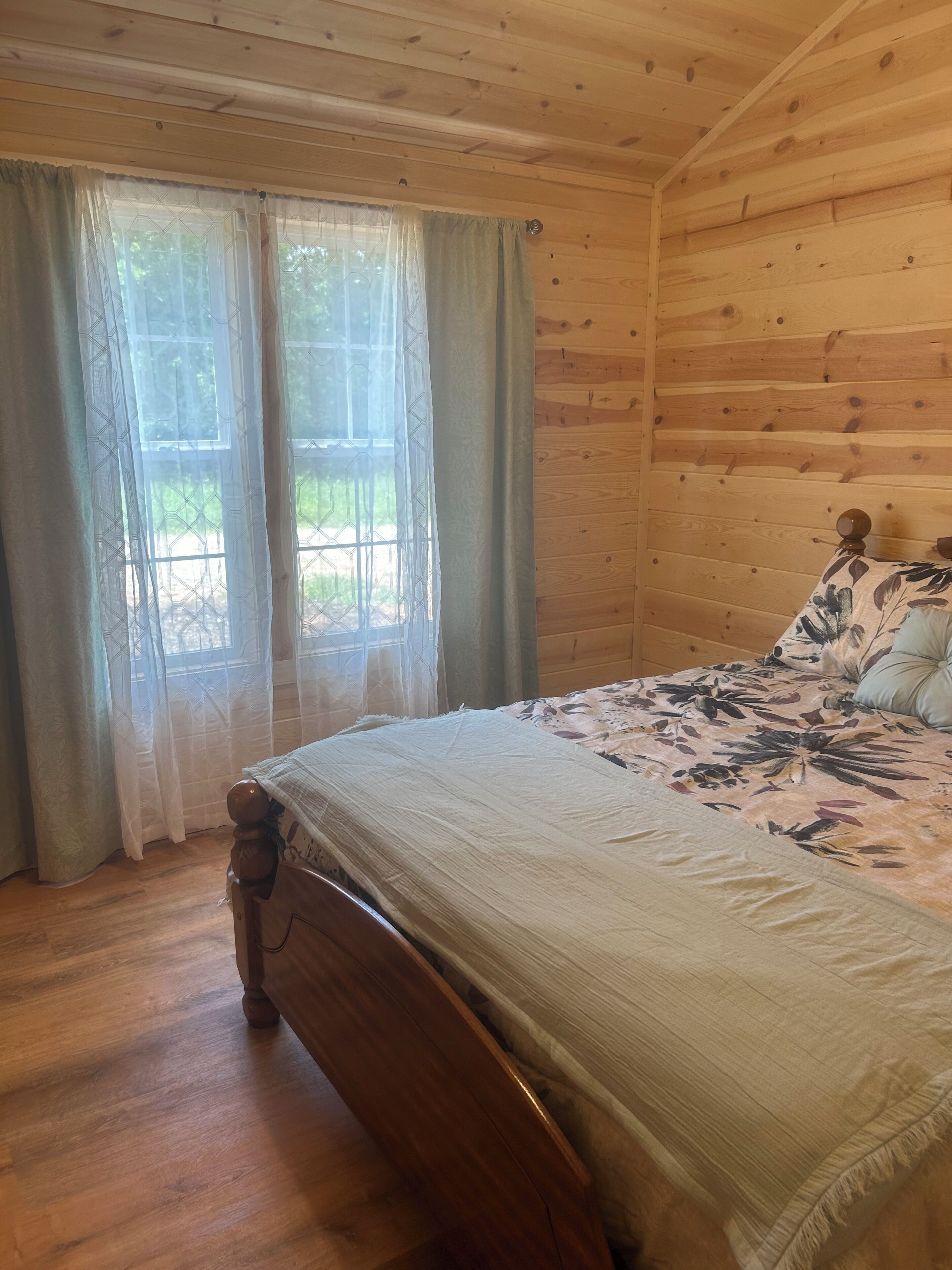 Um quarto com painéis de madeira, uma cama, cortinas e uma janela.