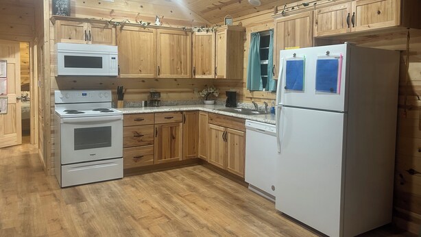 A kitchen with wooden cabinets, a white refrigerator, a stove, and a microwave. - Texas Longhorn Ranch-Private Cabin-Pasture Views (Licking)
