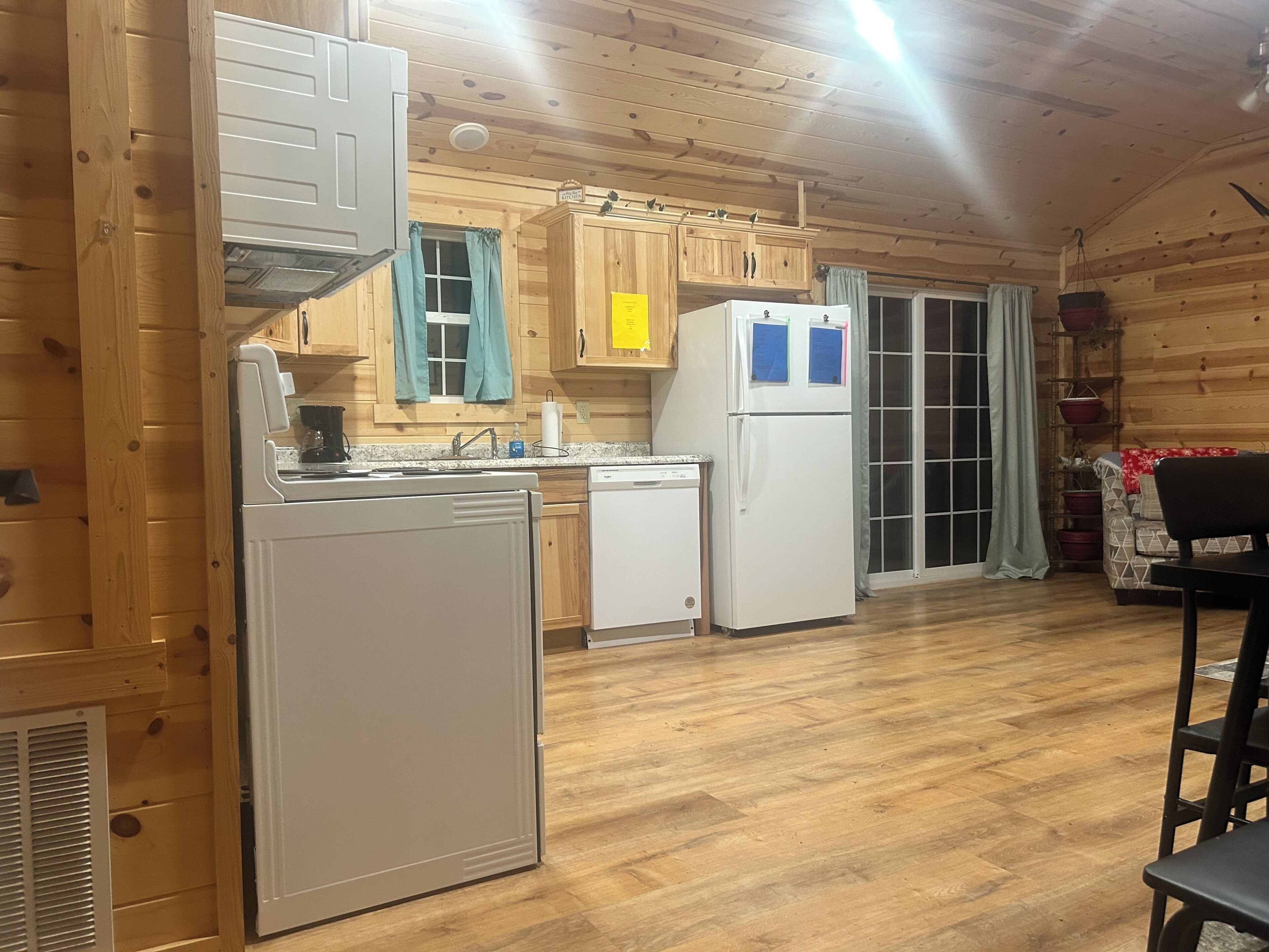 L’intérieur d’une cabane en bois comprend un coin cuisine équipé d’un poêle, d’un évier et d’un réfrigérateur. On y trouve également un coin repas avec une table et des chaises.