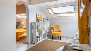 A bedroom with a skylight, a bed, a bookshelf, a yellow armchair, and a small table. - Apartment 'Les Hauts Du Lac' with Lake View and Wi-Fi (Les Sables-d'Olonne)