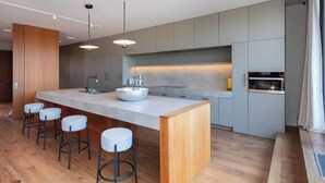 A modern kitchen with a central island, bar stools, and built-in appliances. - Luxury 3+ BR Penthouse Near Jean-Talon Market (Montréal)