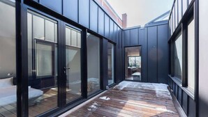 A modern building with large glass doors, a wooden deck, and a visible interior space. - Luxury 3+ BR Penthouse Near Jean-Talon Market (Montréal)