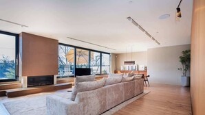A modern living room with a large sofa, a fireplace, and large windows. - Luxury 3+ BR Penthouse Near Jean-Talon Market (Montréal)