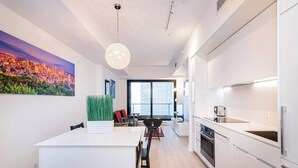 A modern kitchen with white cabinetry, a central island, and a dining area with a view.