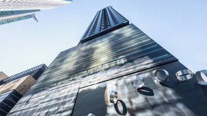 A tall building with a reflective glass facade and a prominent spire.