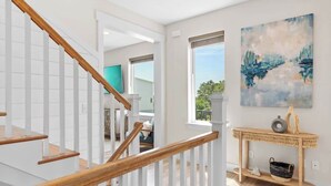 A modern interior with a wooden staircase, a console table, and a large abstract painting. - Family-Friendly Home with Rooftop Lounge (Inlet Beach)