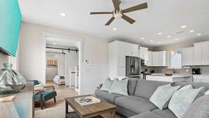A modern living room with a grey sofa, wooden coffee table, and a ceiling fan. - Family-Friendly Home with Rooftop Lounge (Inlet Beach)