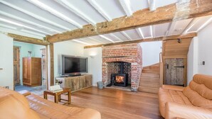 A living room with a fireplace, leather sofas, a TV on a wooden cabinet, and a staircase leading to another room.
