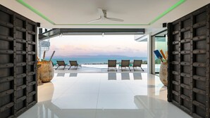 Un interior moderno con un espacio amplio, ventilador de techo y vista al mar.