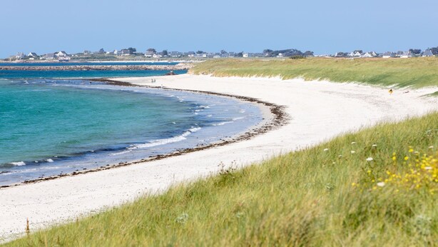 A coastal beach with white sand, clear blue water, and a grassy dune. - Chez Patricia et Patrice by Interhome (Guissény)