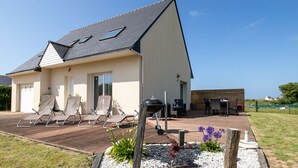 A modern house with a sloped roof, a patio with sun loungers, and a barbecue area. - Chez Patricia et Patrice by Interhome (Guissény)