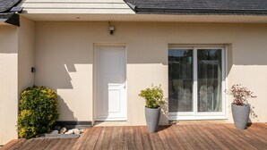A house with a white door, a large sliding glass door, and two potted plants on the porch. - Chez Patricia et Patrice by Interhome (Guissény)